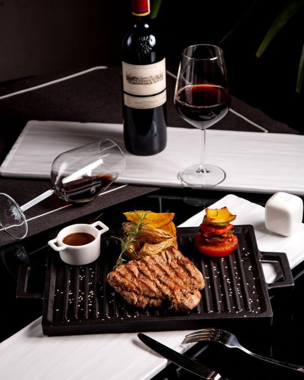 steak served with potatoes grilled vegetables sauce and wine